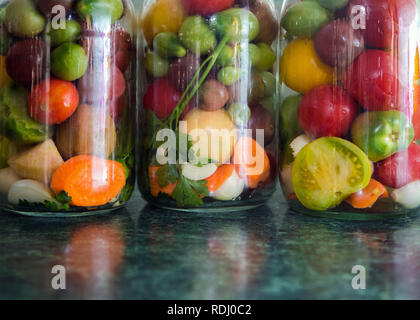 Gläser von eingelegtem Gemüse. Traditionelle marinierte Lebensmittel - Tomaten, Gurken, Zwiebeln Stockfoto