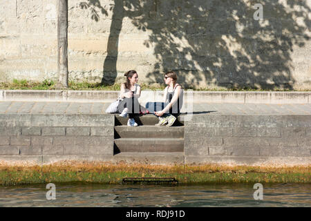 Junge Leute sitzen entlang der Ufer des Canal St-Martin in Paris, Frankreich. Stockfoto