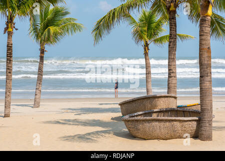 Mein Khe Strand mit einer Abbildung eines jungen Reisenden, traditionelle vietnamesische coracles (runde Wicker Boote) auf dem Sand, Palmen und kommenden Wellen. Stockfoto