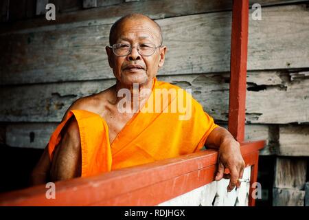 Luang Prabang/Laos - JUL 06 2011: Rauchen Kopf buddhistischer Mönch in seinem Kloster ruht während des Nachmittags Hitze mit Brille Stockfoto