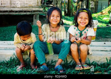 Nong Khiaw/Laos - JUL 06 2011: nette junge Kinder auf eine Spalte vor ihren Bambus und Holz nach Hause sitzen Stockfoto