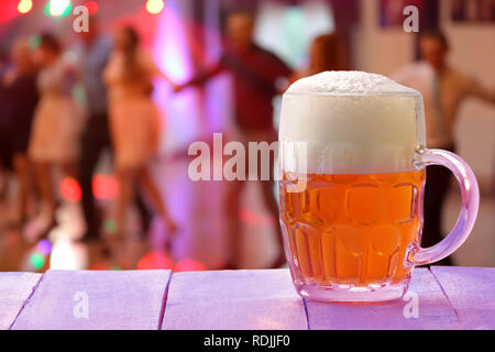 Tanzende Menschen auf einer Party gegen ein Glas Bier und leeren Raum für Text Stockfoto