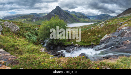 Schöne Panorama Landschaft Bild der Strom fließt über die Felsen in der Nähe von Llyn Ogwen in Snowdonia während eary Herbst mit Tryfan im Hintergrund Stockfoto