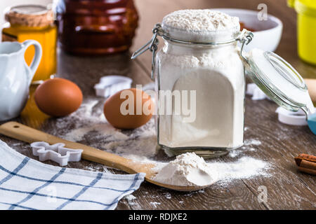 Mehl in einem Glas auf einem Holztisch mit Zutaten Stockfoto