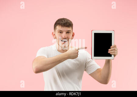Portrait von lächelnden Mann am Laptop mit leeren Bildschirm auf Pink Studio Hintergrund zeigt. Menschliche Gefühle, Mimik Konzept und Werbung Konzept. Stockfoto