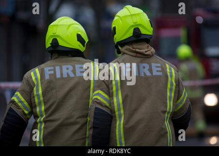 Feuerwehrleute sorgen sich ein Brand in den Räumlichkeiten auf der Walworth Road, am 16. Januar 2019 in London, England. Nach Londoner Feuerwehr, "Zehn Löschfahrzeuge und rund 70 Feuerwehrmänner wurden zu einem Brand in einem Shop mit Wohnungen oben auf der Walworth Road in Walworth genannt. Im Erdgeschoss des Gebäudes durch die Flamme und einen kleinen Teil des Untergeschosses zerstört wurde, im ersten Stock und im zweiten Stock wurden auch beschädigt. Feuerwehrmänner tragen von Atemschutzgeräten gerettet ein Mann und eine Frau aus dem ersten Stock Flachdach mit einer Schiebeleiter. Die Frau wurde an der Szene für Rauch einatmen dann Tak behandelt Stockfoto