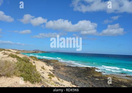 Wüste Küste von Corralejo, Fuerteventura, Spanien. Naturpark Dünen. Türkisfarbene Meer und bewölkt blauer Himmel. Stockfoto