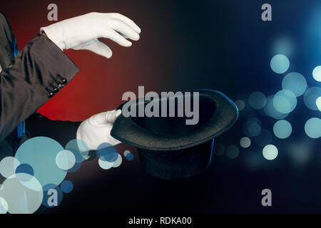 Berufliche Tätigkeit. Showman in Anzug und Handschuhe auf Wand, Tricks mit Hut in der Nähe isoliert aufstehen Stockfoto