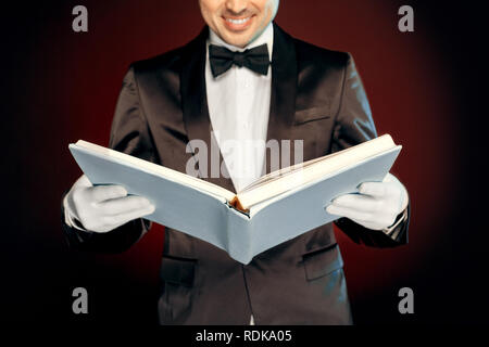 Berufliche Tätigkeit. Magier in Anzug und Handschuhe an der Wand lesen Magic freudige schließen isoliert aufstehen Stockfoto