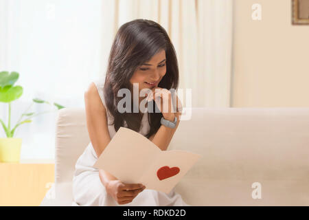 Frau liest romantische Valentinstag Karte zuhause Stockfoto