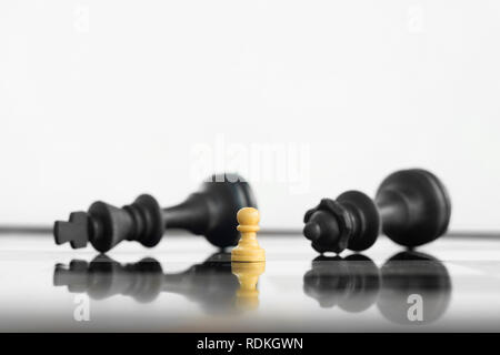Weiß peon Ständigen siegreich vor einem besiegt König und Königin schwarz chess Armee nach der Konfrontation. Stockfoto