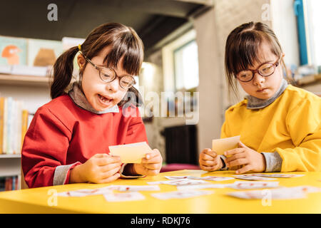 Schwestern mit Down Syndrom spielen mit Karten zusammen Stockfoto
