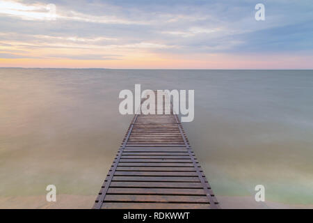 Idyllische mole (Pier) auf dem See. Holzbrücke im Frühling mit blauen See bei Sonnenaufgang. See zum Angeln mit Pier Stockfoto