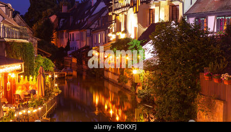 Alte Häuser beleuchtet, kleiner Fluss, Wasser Reflexion in der Nacht im Frühling, Colmar, Frankreich. Stockfoto