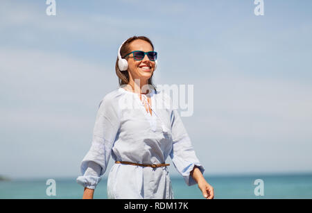 Frau mit Kopfhörer entlang Sommer Strand Stockfoto