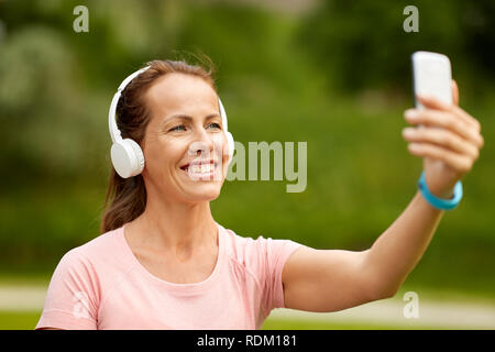 Frau in Handys nimmt selfie per Smartphone im Park Stockfoto