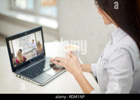 Frau mit Kaffee beobachten Webinar am Laptop Stockfoto