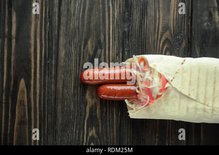 Ausschreibung Wurst in pita Brot auf hölzernen Hintergrund. Foto mit Co Stockfoto