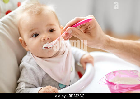 Vater feeding Baby Hochstuhl zu Hause sitzen Stockfoto