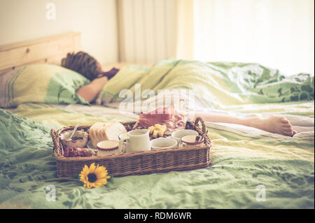 Frühstück im Bett, neben Frau schlafen im Bett, am frühen Morgen Überraschung Stockfoto