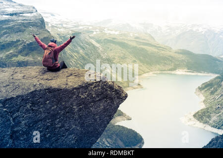 Sportliche Frau posiert auf Trolltunga. Glückliche Wanderer genießen die schönen See und gutes Wetter in Norwegen. Stockfoto