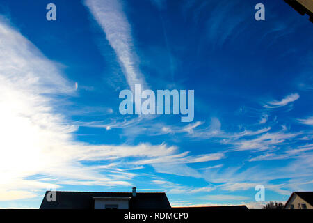 Blauer Himmel mit Wolken vor Häusern Stockfoto