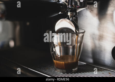 In der Nähe von Glas auf der Espressomaschine, heißen Kaffee gießen vom Auswurfkrümmer. Stockfoto