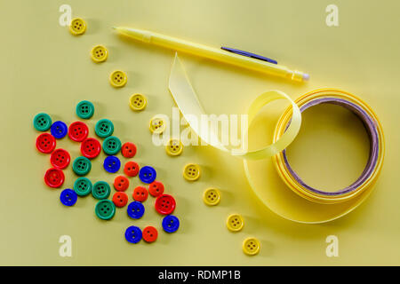 Mehrfarbige Tasten, gelb und Bogen gelben Bleistift auf gelbem Hintergrund table top Stockfoto