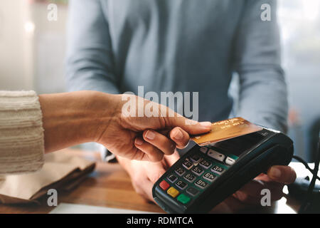 Apotheker akzeptieren Kreditkarte durch das kontaktlose Bezahlen. Frau für den Kauf von Produkten in der Apotheke. Apotheker Hände laden mit Credit Card Reader Stockfoto