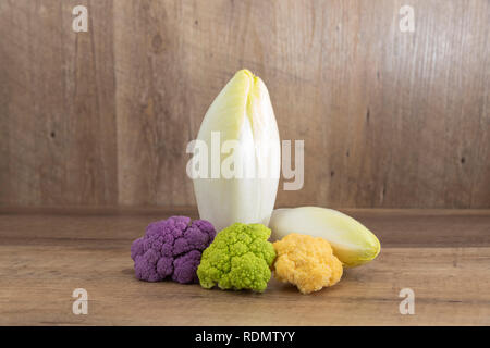 Frische Endivie (cichorium endivie) und decoratif Blumenkohl auf natürlichen Holz- Hintergrund mit markieren und Schatten Stockfoto