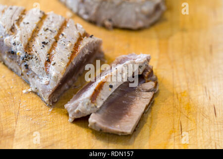 Vom Holzkohlegrill, gewürzt Thunfisch Steaks zubereitet und auf einer hölzernen Schneidebrett in Scheiben geschnitten Stockfoto