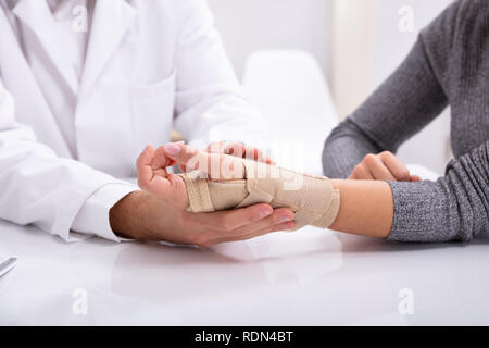 In der Nähe des Doctor's Hand Kontrolle der gebrochenen Hand einer Frau Stockfoto