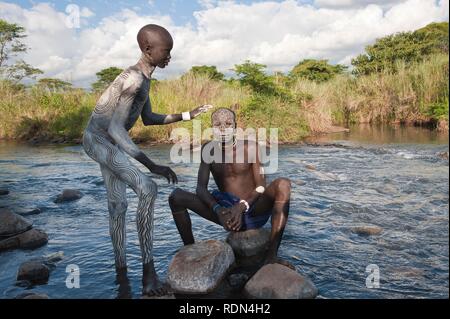 Zwei Surma Männer mit Gesichts- und Körperanwendungen Gemälde im Fluss, Kibish, Omo-tal, Äthiopien, Afrika Stockfoto
