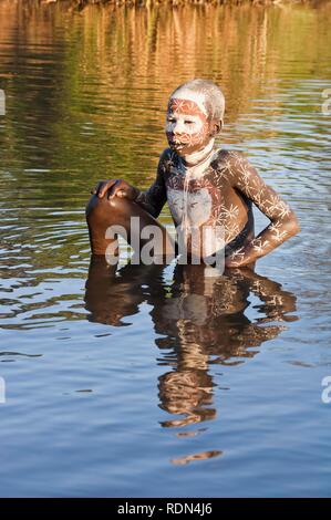 Surma Junge mit Gesichts- und Körperbemalung im Wasser, Kibish, Omo-tal, Äthiopien, Afrika Stockfoto