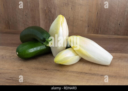 Endivie (cichorium endivie) und Zucchini auf natürlichen Holz- Hintergrund mit markieren und Schatten Stockfoto