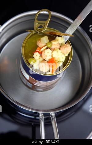 Nacherwärmung ein fertiggericht in eine Blechdose im Wasserbad, Nudelsuppe mit Frikadellen und Gemüse Stockfoto