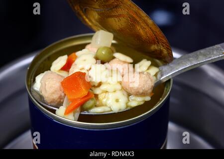 Nacherwärmung ein fertiggericht in eine Blechdose im Wasserbad, Nudelsuppe mit Frikadellen und Gemüse Stockfoto