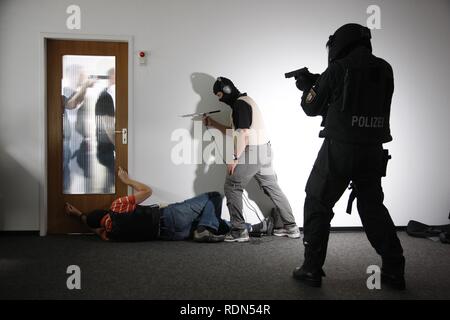 Mitglieder der technischen Arbeitsgruppe der Spezialeinheit der Polizei Hören zu einem Gespräch hinter einer Tür, wo eine Geisel wurde Stockfoto