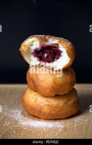 Donuti mit Kirschen auf schwarzem Hintergrund. Frische Donuts. Stockfoto