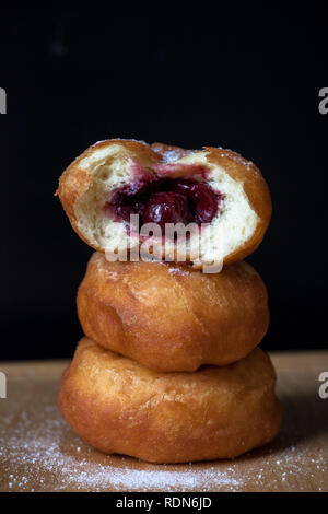 Donuti mit Kirschen auf schwarzem Hintergrund. Frische Donuts. Stockfoto