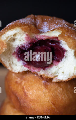 Donuti mit Kirschen auf schwarzem Hintergrund. Frische Donuts. Stockfoto