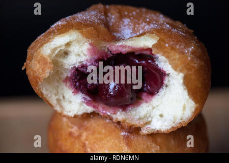 Donuti mit Kirschen auf schwarzem Hintergrund. Frische Donuts. Stockfoto