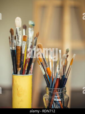Pinsel in zwei Gläser mit staffelei im Hintergrund Stockfoto