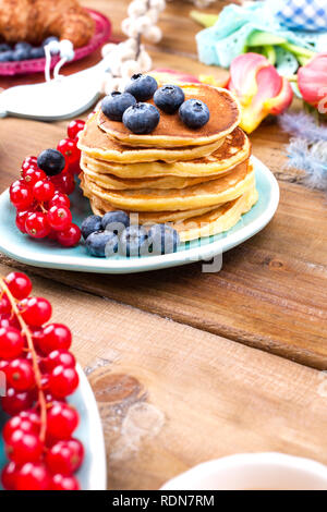 Sie hausgemachte Kuchen Croissants zum Frühstück mit Heidelbeeren und Johannisbeeren und Kaffee, auf einer hölzernen Hintergrund und Frühling Tulpen. Freier Platz für Text Stockfoto