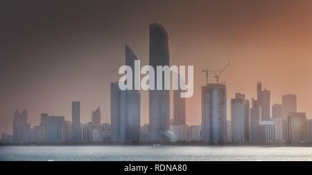 Blick auf die Skyline von Abu Dhabi an Misty Sonnenuntergang, Vereinigte Arabische Emirate Stockfoto