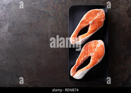 Frischer Lachs Fisch Steaks auf schwarzem Hintergrund oben Stockfoto