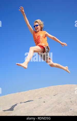 Junge spielerisch das Springen von einer Düne Stockfoto