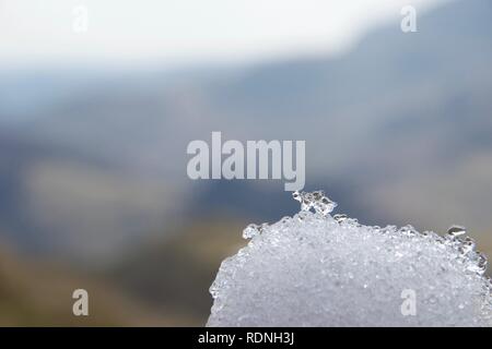 Scharf geschossen von Weiß und klar Schnee- und Eiskristalle auf einem Schneeball. Berge im englischen Lake District (Cumbria, UK) unscharf im Hintergrund. Stockfoto