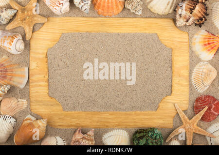 Schönen Holzrahmen, Sterne und Muscheln im Sand Hintergrund, mit Platz für Ihr Bild, Text. Ansicht von oben. Stockfoto