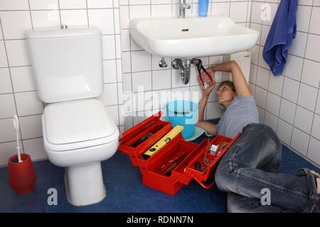 Junge Frau bei der Reparatur eines defekten Wasserhahn im Badezimmer Stockfoto
